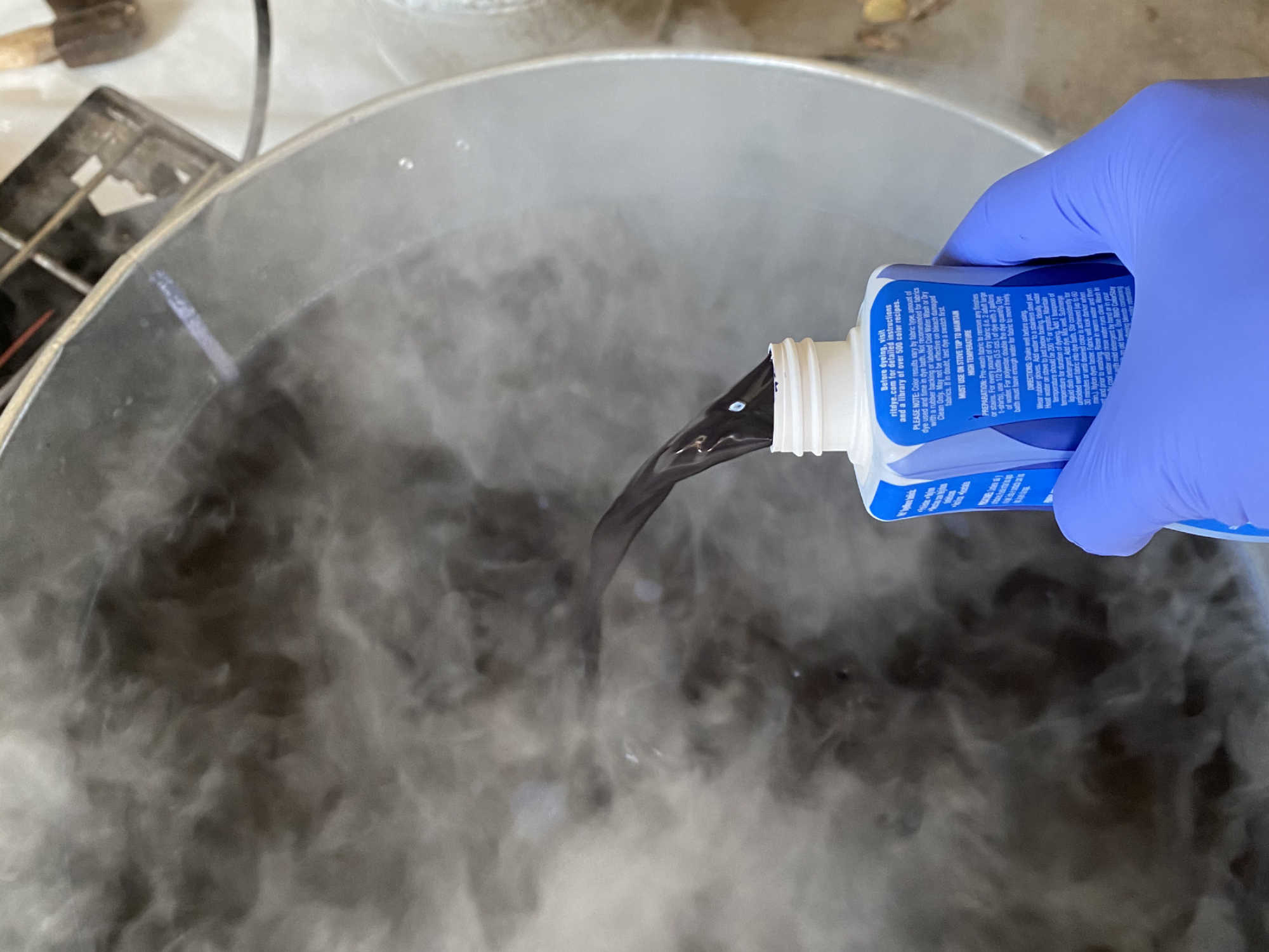 Blue fabric dye is added to a tub of boiling water.